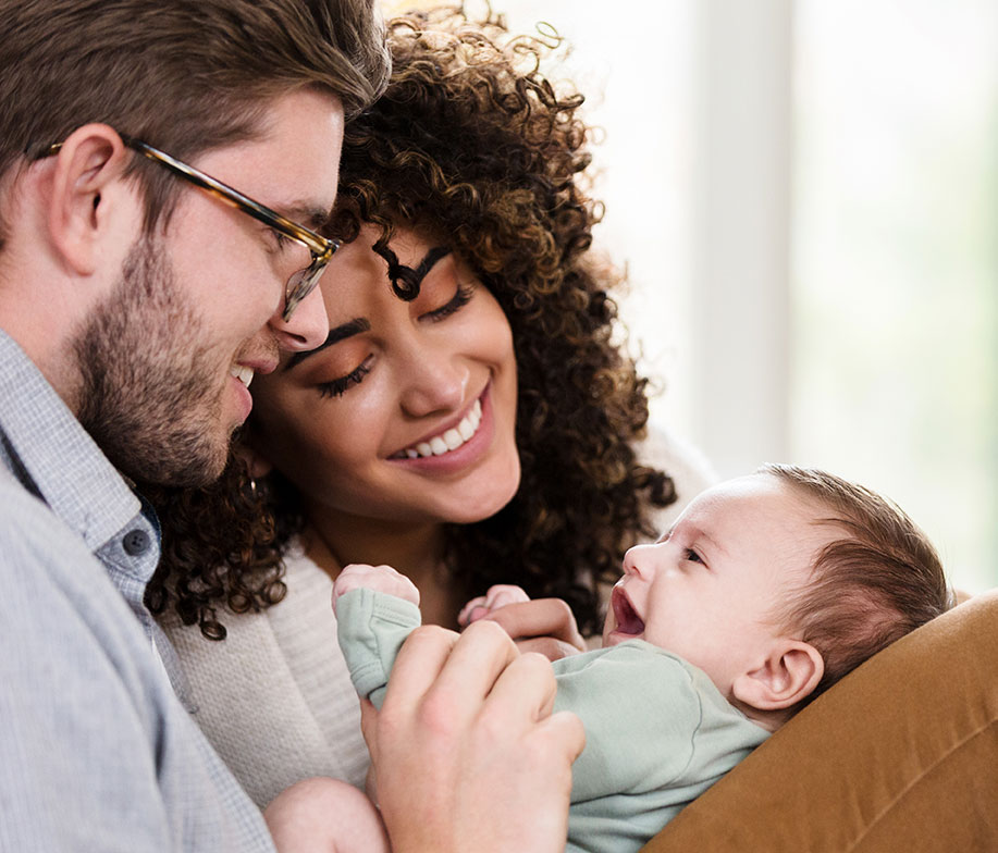 young couple holding and smiling at their newborn baby